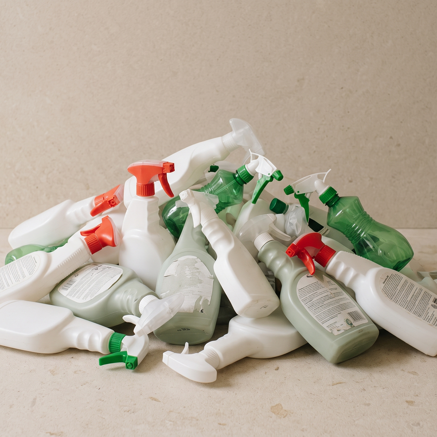 A pile of discarded plastic cleaning spray bottles